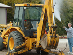 Man pressure washing heavy equipment