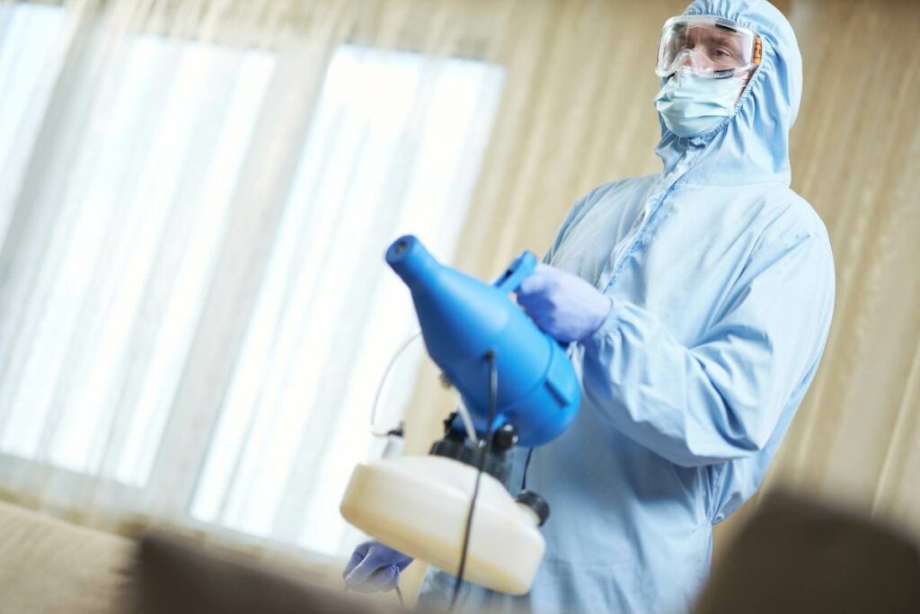Man in hazmat suite using a disinfecting machine