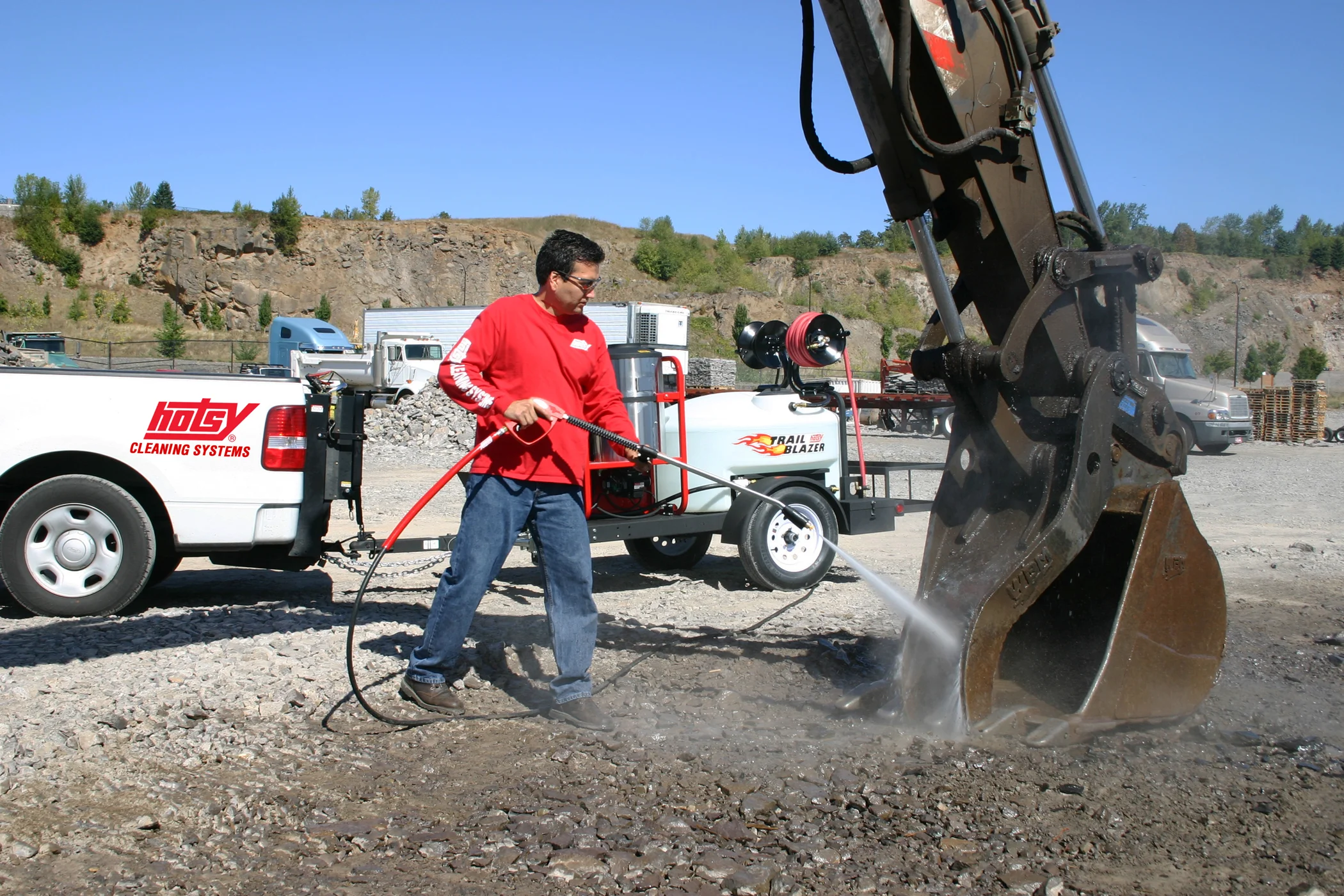 A piece of heavy equipment is getting cleaned by an industrial pressure washer.