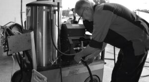 Technician performing maintenance on an industrial Hotsy pressure washer in a workshop