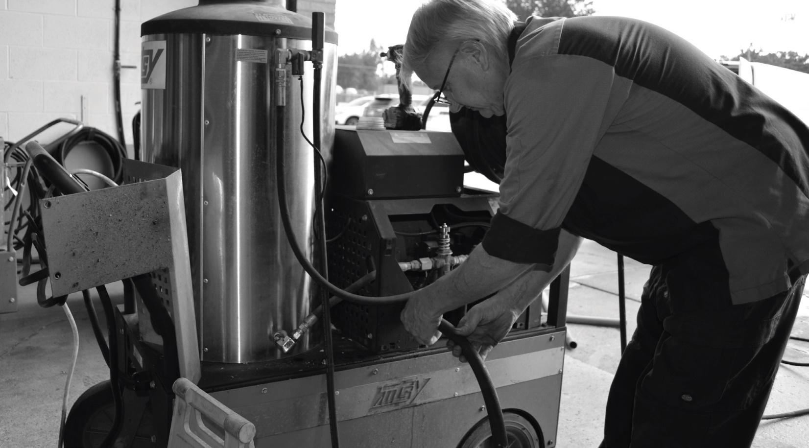 Technician performing maintenance on an industrial Hotsy pressure washer in a workshop Technician performing maintenance on an industrial Hotsy pressure washer in a workshop