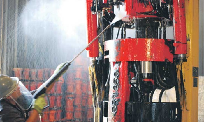 Worker pressure washing heavy industrial equipment to remove grease and buildup