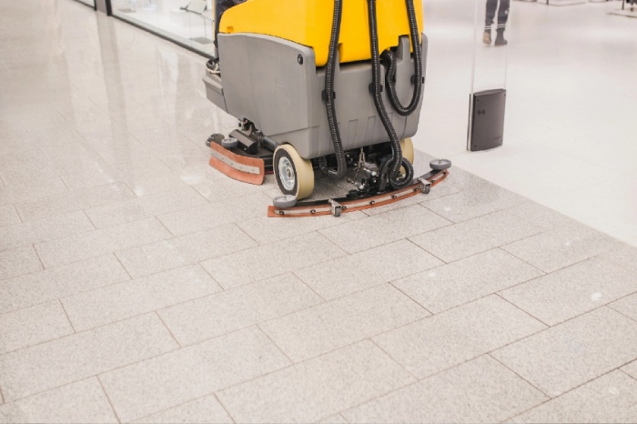 Commercial floor sweeper cleaning tile floors of transportation facility